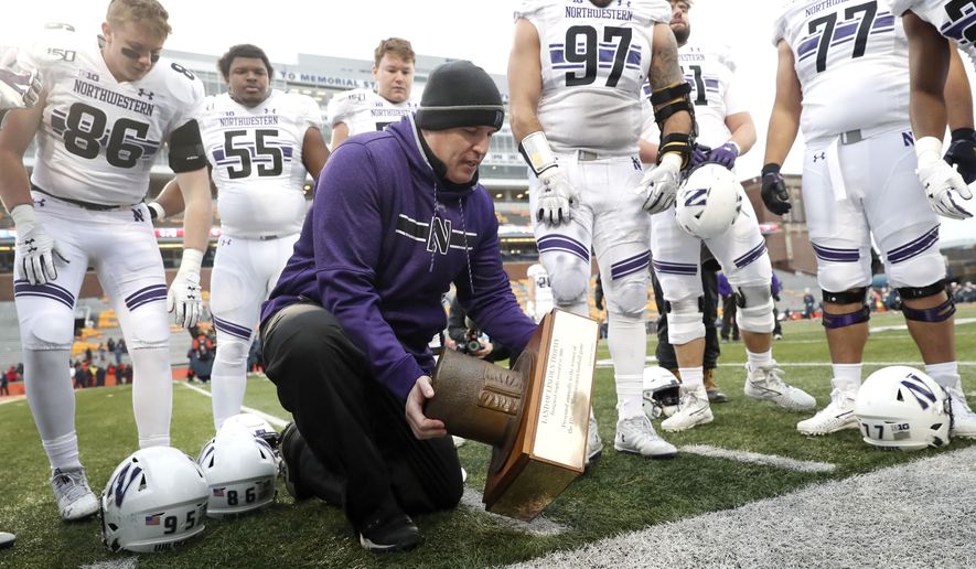 Northwestern head coach Pat Fitzgerald picks up the Land of Lincoln trophy after an NCAA college football game against Illinois, Saturday, Nov. 30, 2019, in Champaign, Ill. Northwestern won 29-10. (AP Photo/Charles Rex Arbogast)