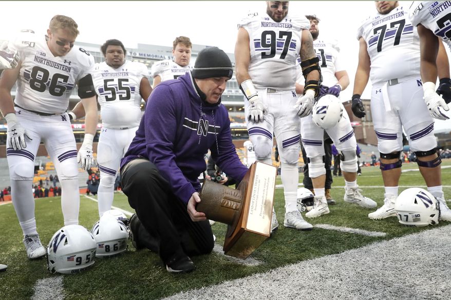 Northwestern head coach Pat Fitzgerald picks up the Land of Lincoln trophy after an NCAA college football game against Illinois, Saturday, Nov. 30, 2019, in Champaign, Ill. Northwestern won 29-10. (AP Photo/Charles Rex Arbogast)