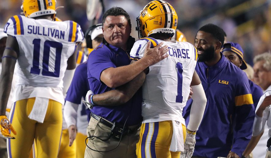 LSU coach Ed Orgeron hugs wide receiver Ja'Marr Chase (1) on the sideline after his touchdown reception in the first half of an NCAA college football game against Texas A&M in Baton Rouge, La., Saturday, Nov. 30, 2019. (AP Photo/Gerald Herbert)