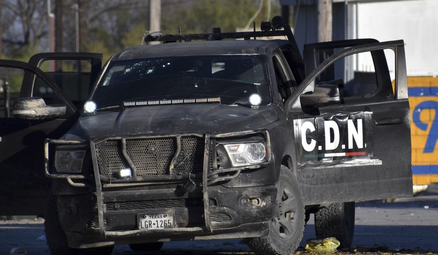 A damaged pick up marked with the initials C.D.N., that in Spanish stand for Cartel of the Northeast, is on the streets after a gun battle between Mexican security forces and suspected cartel gunmen, in Villa Union, Mexico, Saturday, Nov. 30, 2019. At least 14 people were killed, four of them police officers, after an armed group in a convoy of trucks stormed the town, in Coahuila state, prompting security forces to intervene, state Gov. Miguel Riquelme Solis said. (AP Photo/Gerardo Sanchez)
