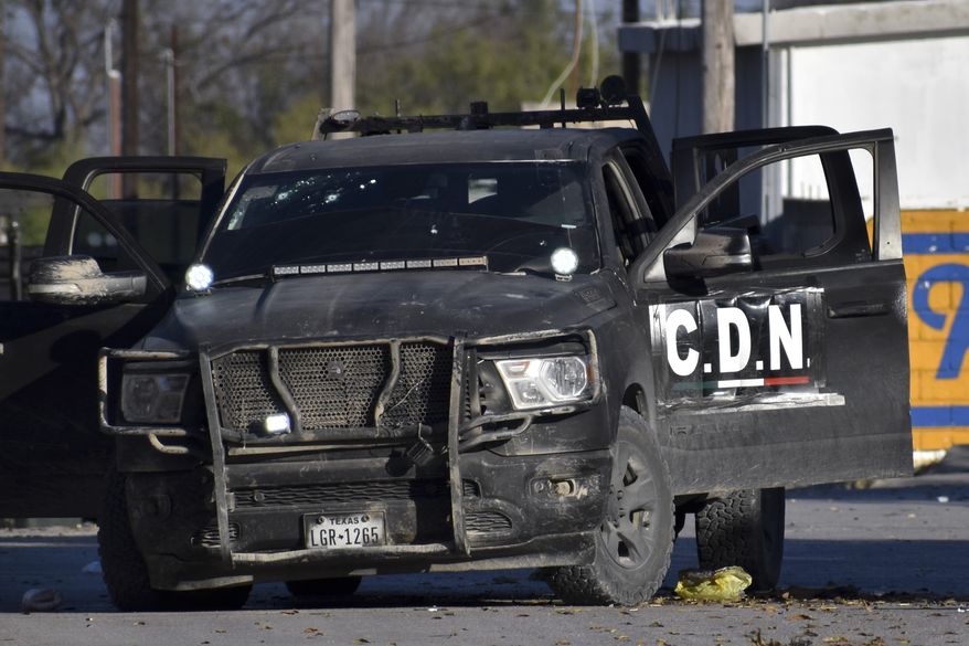 A damaged pick up marked with the initials C.D.N., that in Spanish stand for Cartel of the Northeast, is on the streets after a gun battle between Mexican security forces and suspected cartel gunmen, in Villa Union, Mexico, Saturday, Nov. 30, 2019. At least 14 people were killed, four of them police officers, after an armed group in a convoy of trucks stormed the town, in Coahuila state, prompting security forces to intervene, state Gov. Miguel Riquelme Solis said. (AP Photo/Gerardo Sanchez)