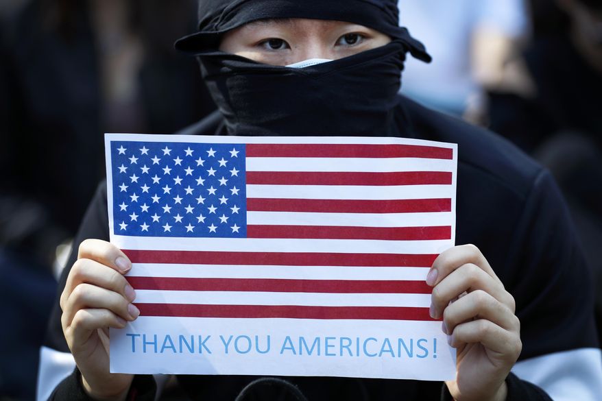 A protester holds a placard carrying an American flag during a rally in Hong Kong, Sunday, Dec. 1, 2019. Hong Kong protesters carrying American flags and banners appealing to President Donald Trump are rallying in the semi-autonomous Chinese territory. (AP Photo/Vincent Thian) **FILE**