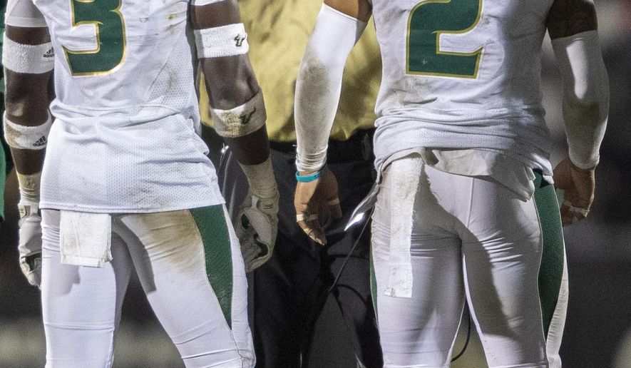 South Florida coach Charlie Strong talks to defensive backs Vincent Davis Jr. (3) and Nick Roberts (2) during the first half of the team's NCAA college football game against Central Florida, Friday, Nov. 29, 2019, in Orlando, Fla. (AP Photo/Willie J. Allen Jr.)