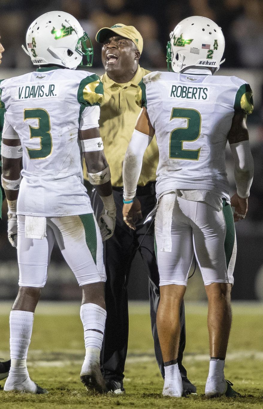 South Florida coach Charlie Strong talks to defensive backs Vincent Davis Jr. (3) and Nick Roberts (2) during the first half of the team's NCAA college football game against Central Florida, Friday, Nov. 29, 2019, in Orlando, Fla. (AP Photo/Willie J. Allen Jr.)