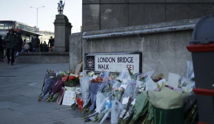 Tributes placed by the southern end of London Bridge in London, Monday, Dec. 2, 2019. London Bridge reopened to cars and pedestrians Monday, three days after a man previously convicted of terrorism offenses stabbed two people to death and injured three others before being shot dead by police. (AP Photo/Matt Dunham)