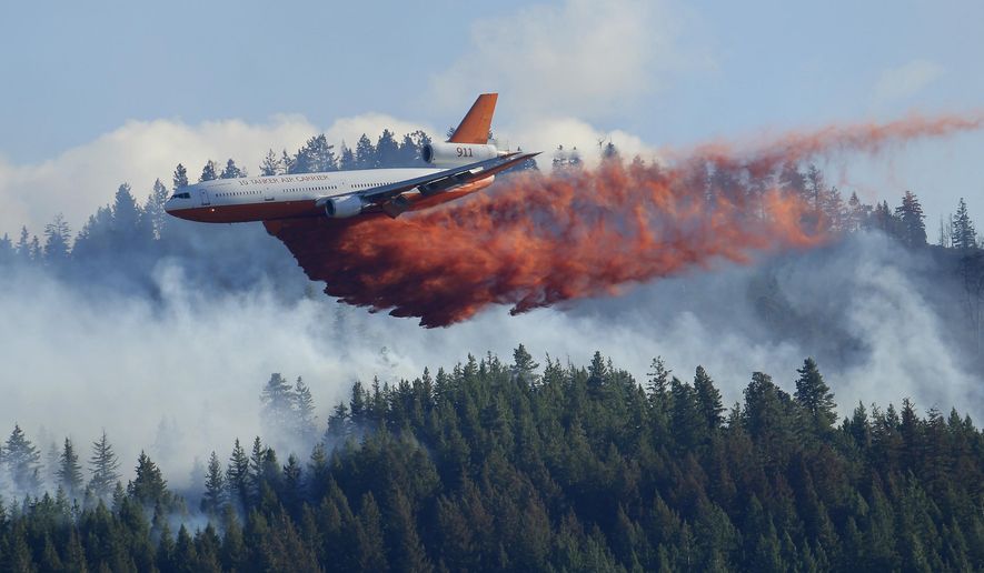 FILE - In this Aug. 21, 2015 file photo, a tanker airplane drops fire retardant on a wildfire burning near Twisp, Wash. The state's commissioner of Public Lands released a proposal Monday, Dec. 2, 2019, that provides some $63 million each year to fight wildfires and take steps to prevent them in the first place. (AP Photo/Ted S. Warren, File)