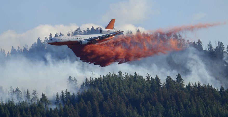FILE - In this Aug. 21, 2015 file photo, a tanker airplane drops fire retardant on a wildfire burning near Twisp, Wash. The state's commissioner of Public Lands released a proposal Monday, Dec. 2, 2019, that provides some $63 million each year to fight wildfires and take steps to prevent them in the first place. (AP Photo/Ted S. Warren, File)