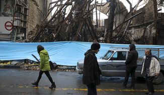 In this Nov. 20, 2019, file photo, people walk past buildings that were burned during recent protests, in Shahriar, Iran, some 40 kilometers (25 miles) southwest of the capital, Tehran. Amnesty International says at least 208 people in Iran have been killed amid protests over sharply rising gasoline prices and a subsequent crackdown by security forces. The country has yet to release any nationwide statistics about the unrest last month. (AP Photo/Vahid Salemi, File)
