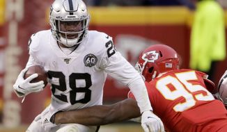 Oakland Raiders running back Josh Jacobs (28) tries to break a tackle by Kansas City Chiefs defensive tackle Chris Jones (95) during the first half of an NFL football game in Kansas City, Mo., Sunday, Dec. 1, 2019. (AP Photo/Charlie Riedel)
