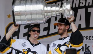 FILE - In this Wednesday, June 14, 2017, file photo, Pittsburgh Penguins goalies Marc-Andre Fleury, left, and Matt Murray hold the Stanley Cup on stage after riding in the Stanley Cup victory parade in Pittsburgh. Managing top goaltenders’ schedules is the NHL’s version of load management. Each of the past five Stanley Cup-winning goalies started fewer than 60 games in the regular season, along with three of the past five runners up. (AP Photo/Gene J. Puskar, File)