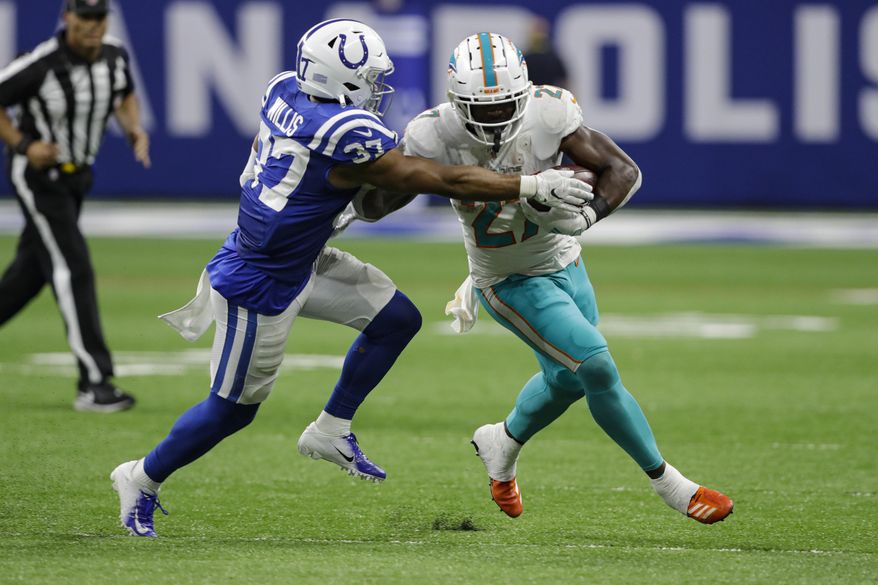 File-This Nov. 10, 2019, file photo shows Indianapolis Colts safety Khari Willis (37) tackling Miami Dolphins running back Kalen Ballage (27) during the second half of an NFL football game in Indianapolis. Ballage’s historically unproductive season ended Tuesday, Dec. 3, 2019, when he was placed on injured reserve by the Dolphins. Ballage hurt his left leg in Sunday’s victory over Philadelphia. The second-year pro finishes the season with 135 yards in 74 carries. His 1.8-yard average is the worst by a running back with at least 70 carries since Phil Sarboe had a 1.2-yard average for two teams in 1936. (AP Photo/Darron Cummings, File)