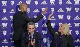 Washington NCAA college football head coach Chris Petersen, center, applauds as defensive coordinator Jimmy Lake, left, high-fives athletic director Jen Cohen after speaking during a news conference about Petersen&#x27;s decision to resign and Lake taking over his job, Tuesday, Dec. 3, 2019, in Seattle. Petersen unexpectedly resigned on Monday, a shocking announcement with the Huskies coming off a 7-5 regular season and bound for a sixth straight bowl game under his leadership. Petersen will coach Washington in a bowl game, his final game in charge. (AP Photo/Elaine Thompson)