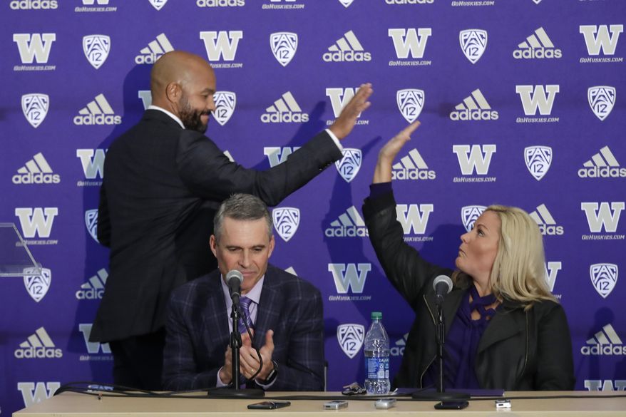 Washington NCAA college football head coach Chris Petersen, center, applauds as defensive coordinator Jimmy Lake, left, high-fives athletic director Jen Cohen after speaking during a news conference about Petersen&#x27;s decision to resign and Lake taking over his job, Tuesday, Dec. 3, 2019, in Seattle. Petersen unexpectedly resigned on Monday, a shocking announcement with the Huskies coming off a 7-5 regular season and bound for a sixth straight bowl game under his leadership. Petersen will coach Washington in a bowl game, his final game in charge. (AP Photo/Elaine Thompson)