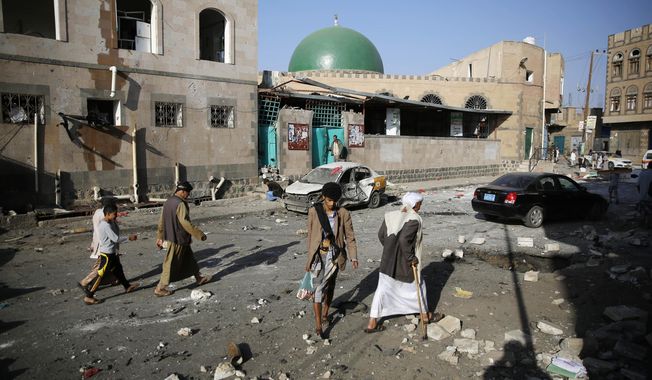 FILE - In this Sept. 3, 2015, file photo people walk at the site of a car bomb attack next to a Shiite mosque in Sanaa, Yemen. Yemen’s civil war has exacted an enormous toll on people with disabilities, who find themselves on the margins of society and excluded from badly needed humanitarian assistance, Amnesty International said in a report released Tuesday, Dec. 3, 2019. (AP Photo/Hani Mohammed, File)