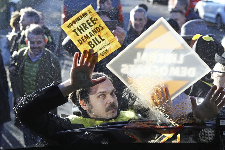 Environmental pressure group Extinction Rebellion protesters are dressed as bees and glue themselves to the front of Liberal Democrats Party bus carrying party leader Jo Swinson, during a visit to a youth centre in London, while on the General Election campaign trail, Wednesday Dec. 4, 2019. The UK goes to the polls in a General Election on Dec. 12. (Aaron Chown/PA via AP)