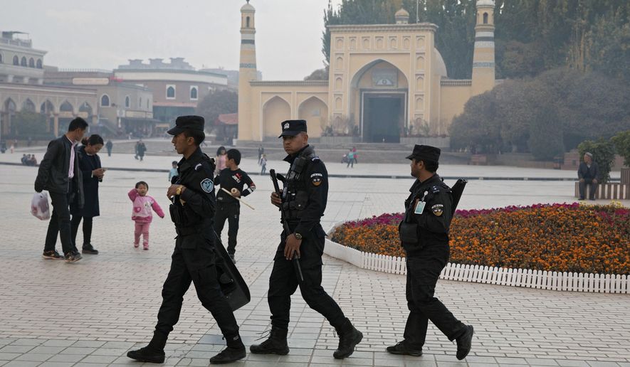 FILE - In this Nov. 4, 2017, file photo, Uighur security personnel patrol near the Id Kah Mosque in Kashgar in western China's Xinjiang region. China on Wednesday, Dec. 4, 2019, has responded with swift condemnation after U.S. Congress overwhelmingly approved a bill targeting its mass crackdown on ethnic Muslim minorities. (AP Photo/Ng Han Guan, File)