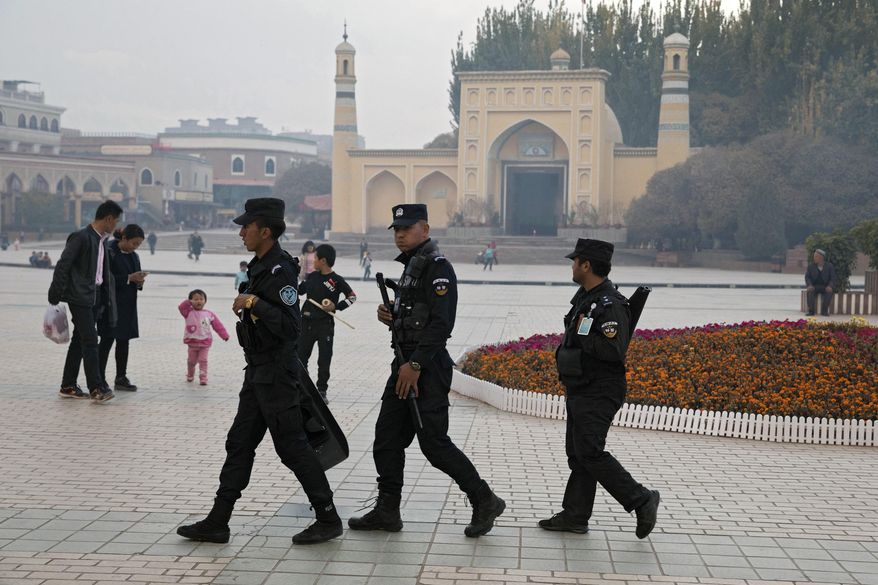 FILE - In this Nov. 4, 2017, file photo, Uighur security personnel patrol near the Id Kah Mosque in Kashgar in western China's Xinjiang region. China on Wednesday, Dec. 4, 2019, has responded with swift condemnation after U.S. Congress overwhelmingly approved a bill targeting its mass crackdown on ethnic Muslim minorities. (AP Photo/Ng Han Guan, File)