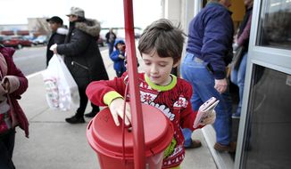 Cameron Bray donates to the the Salvation Army outside of Hobby Lobby in Janesville, Wisconsin, on Saturday, Nov. 29, 2019. Bell ringer Debi Pulver averaged $63 raised per hour while ringing the ball last year. (Anthony Wahl/The Janesville Gazette via AP) **FILE**