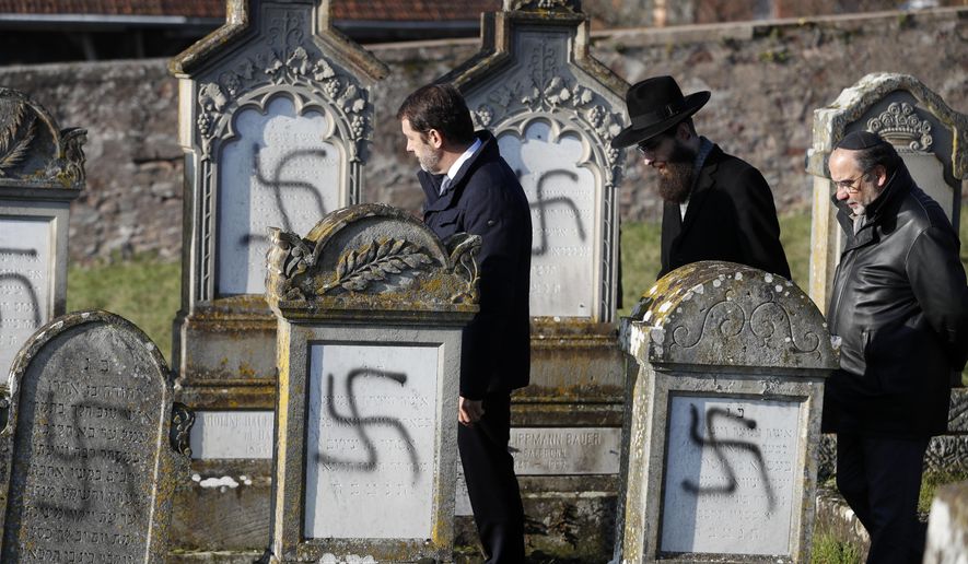 French Interior Minister Christophe Castaner, center, followed by Strasbourg chief Rabbi Harold Abraham Weill, second right, walk amid vandalized tombs in the Jewish cemetery of Westhoffen, west of the city of Strasbourg, eastern France, Wednesday, Dec. 4, 2019. Regional authorities in eastern France say vandals have scrawled anti-Semitic inscriptions, including swastikas spray-painted in black, on 107 tombs in a Jewish cemetery. (AP Photo/Jean-Francois Badias)