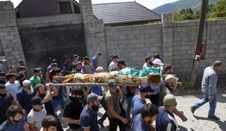 FILE-In this Aug. 29, 2019 file photo people carry the body of the victim who has been identified as Zelimkhan Khangoshvili, a Georgian Muslim during the funeral in Duisi village, the Pankisi Gorge valley, in Georgia. Germany’s foreign ministry says it has expelled two Russian diplomats after prosecutors announced they suspected Moscow’s involvement in the brazen daylight slaying of a Georgian man in Berlin. (AP Photo/Zurab Tsertsvadze)