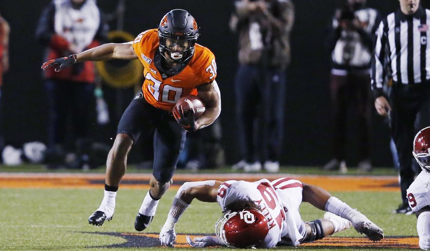 Oklahoma State running back Chuba Hubbard (30) avoids a tackle by Oklahoma linebacker Caleb Kelly (19) in the first half of an NCAA college football game in Stillwater, Okla., Saturday, Nov. 30, 2019. (AP Photo/Sue Ogrocki)