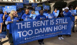 Supporters of the Rental Affordability Act hold up signs during a news conference Thursday, Dec. 5, 2019, in Los Angeles. (AP Photo/Michael Blood)