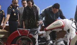 Indonesian Finance Minister Sri Mulyani Indrawati, second from right, and Minister of State-Owned Enterprises Eric Thohir, right, inspect a Harley Davidson motorcycle found by customs officials on a Garuda Indonesia&#39;s new Airbus A330-900 being delivered from France, prior to the start of a press conference in Jakarta, Indonesia, Thursday, Dec. 5, 2019. Thohir said he will fire and seek the prosecution of the head of the national airline after he was implicated in the smuggling the motorcycle into the country on the new jet. (AP Photo/Achmad Ibrahim)