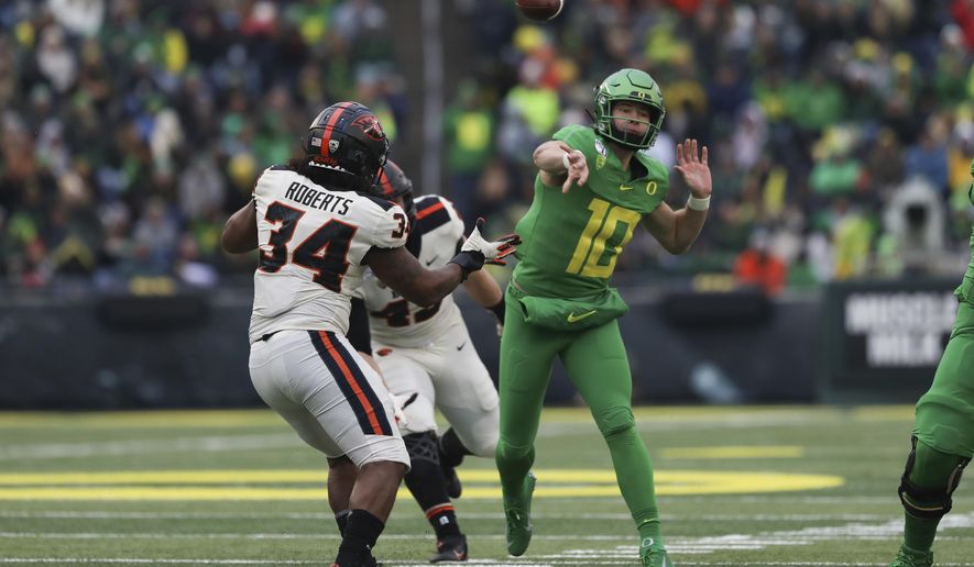 Oregon quarterback Justin Herbert (10) throws a pass away from Oregon State inside linebacker Avery Roberts (34) and defensive lineman Simon Sandberg (45) during the second half of an NCAA college football game in Eugene, Ore., Saturday, Nov. 30, 2019. (AP Photo/Amanda Loman)