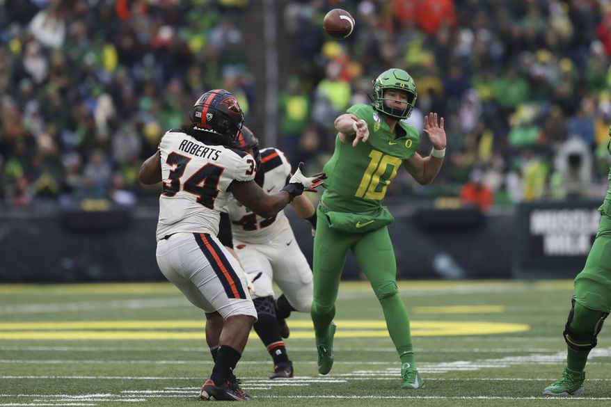 Oregon quarterback Justin Herbert (10) throws a pass away from Oregon State inside linebacker Avery Roberts (34) and defensive lineman Simon Sandberg (45) during the second half of an NCAA college football game in Eugene, Ore., Saturday, Nov. 30, 2019. (AP Photo/Amanda Loman)