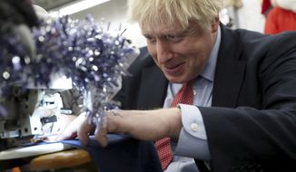 Britain&#39;s Prime Minister Boris Johnson tries to operate a sewing machine decorated for Christmas, during an election campaign stop at John Smedley Mill in Matlock, England, Thursday Dec. 5, 2019. The UK goes to the polls in a General Election on Dec. 12. (Hannah McKay/Pool via AP)