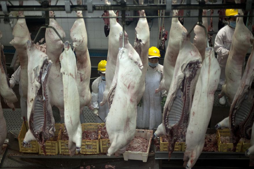 FILE - In this Tuesday June 4, 2013, file photo, employees work at a pork processing plant owned by Henan Shuanghui Group Ltd., in Luohe, in central China's Henan province. China's finance ministry Friday, Dec. 6, 2019, said Beijing is waiving tariff hikes on U.S. soybeans and pork while the two sides negotiate a trade deal. China promised in September to lift the tariffs but no details were released. (AP Photo/Alexander F. Yuan)