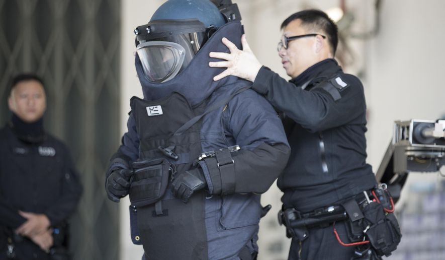 A police officer from the bomb disposal squad putting on protective gear during a demonstration for media in Hong Kong, Friday, Dec. 6, 2019. Hong Kong's much-maligned police force provided a rare behind-the-scenes look Friday at its bomb disposal squad to show the potentially deadly destructive force of homemade explosives seized during months of protests that have shaken the Chinese territory. (AP Photo/Vincent Thian)