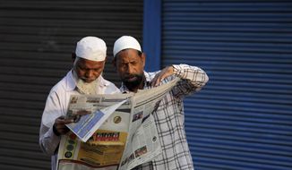 FILE - In this Sunday, Nov. 10, 2019, file photo, Muslims read about the verdict in a decades-old land title dispute between Muslims and Hindus in a newspaper in Ayodhya, India. India’s largest Muslim political groups are divided over how to respond to a recent Supreme Court ruling that favors Hindus’ right to a disputed site 27 years after Hindu nationalist mobs tore down a 16th-century mosque there, unleashing torrents of religious-motivated violence. (AP Photo/Rajesh Kumar Singh, File)