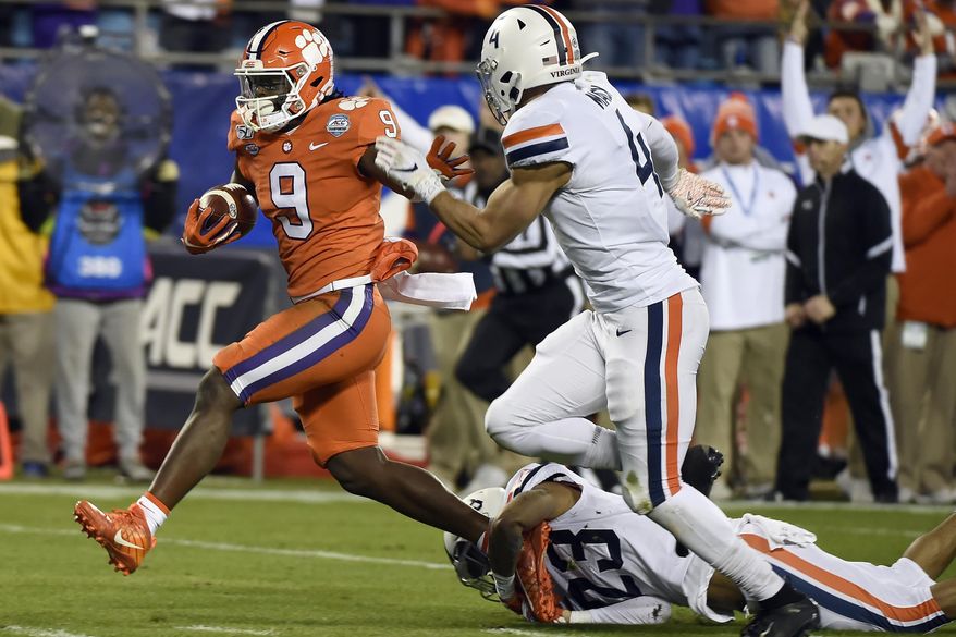 Clemson running back Travis Etienne (9) escapes the tackle attempt by Virginia cornerback Heskin Smith (23) and Virginia linebacker Jordan Mack (4) during the first half of the Atlantic Coast Conference championship NCAA college football game in Charlotte, N.C., Saturday, Dec. 7, 2019. Etienne scored a touchdown on the play. (AP Photo/Mike McCarn)