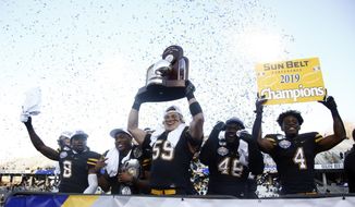 Appalachian State players, from left, defensive back Shemar Jean-Charles (8), running back Darrynton Evans (3), linebacker Jordan Fehr (59), defensive lineman Demetrius Taylor (48) and running back Daetrich Harrington (4) celebrate on stage following their 45-38 win over Louisiana-Lafayette in an NCAA college football game for the Sun Belt Football Championship, Saturday, Dec. 7, 2019, in Boone, N.C. (AP Photo/Brian Blanco)