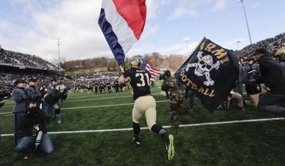 Army defensive back Caleb McNeill carries the flag of France onto the field before an NCAA college football game against Tulane, Saturday, Nov. 14, 2015, in West Point, N.Y. (AP Photo/Mike Groll)