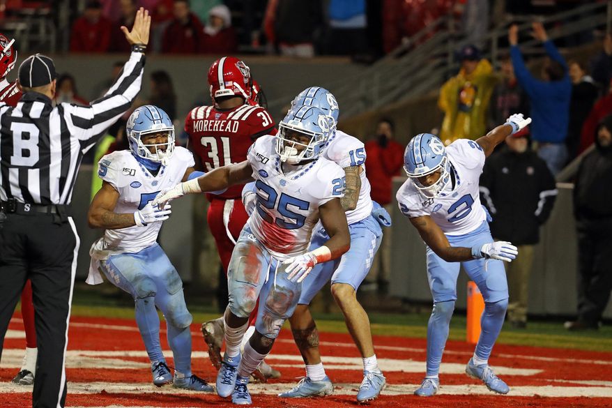 North Carolina's Javonte Williams (25) celebrates a touchdown against North Carolina State with teammates during the second half of an NCAA college football game in Raleigh, N.C., Saturday, Nov. 30, 2019. (AP Photo/Karl B DeBlaker)
