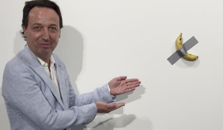 In this Dec. 4, 2019 photo, gallery owner Emmanuel Perrotin poses next to Maurizio Cattlelan's "Comedian" at the Art Basel exhibition in Miami Beach, Fla. The work sold for $120,000. (AP Photo/Siobhan Morrissey)
