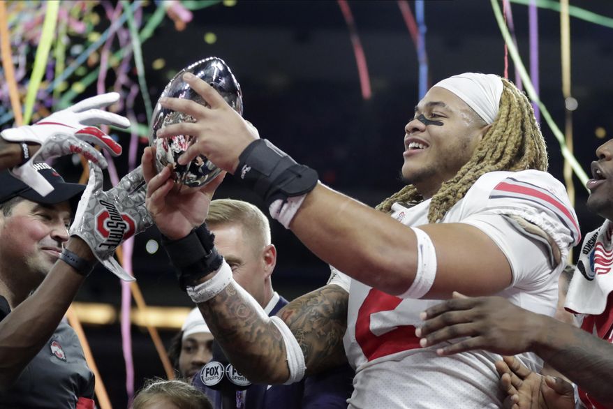 Ohio State defensive end Chase Young (2) holds the trophy following the team's 34-21 win over Wisconsin in the Big Ten championship NCAA college football game, early Sunday, Dec. 8, 2019, in Indianapolis. (AP Photo/Michael Conroy)