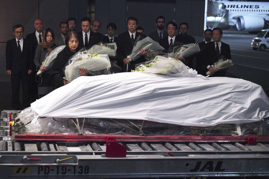 Family members and officials lay flowers at the coffin of slain Japanese doctor Tetsu Nakamura during a ceremony after transporting his body to his homeland, at Narita International Airport in Narita, east of Tokyo Sunday, Dec. 8, 2019. (AP Photo/Eugene Hoshiko)