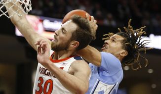 Virginia forward Jay Huff (30) and North Carolina guard Cole Anthony, right, collide under the basket during the first half of an NCAA college basketball game in Richmond, Va., Sunday, Dec. 8, 2019. (AP Photo/Steve Helber)