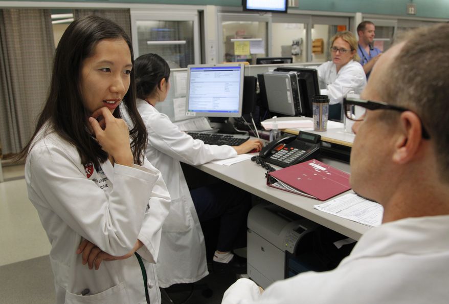 In this Tuesday, Aug. 14, 2012, file photo Leana Wen, of Boston, left, who is doing her medical residency in emergency medicine at Harvard-affiliated Brigham and Women&#x27;s Hospital and Massachusetts General Hospital, speaks with Josh Kosowsky, clinical director of emergency medicine, right, in the emergency department at Brigham and Women&#x27;s Hospital, in Boston. Wen chose emergency medicine because the hours are more flexible than those of primary care physicians. (AP Photo/Steven Senne) ** FILE **