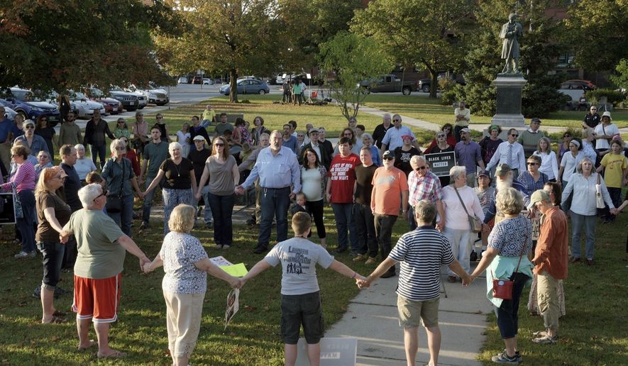 FILE - In this Sept. 12, 2017, file photo, a chorus of "We Shall Overcome" rises from a gathering against racism in Broad Street Park in Claremont, N.H. The demonstration was inspired by violence in the preceding month against an 8-year-old biracial boy who was nearly hanged while he played with a group of teenagers outside his home. On Tuesday, Dec. 10, 2019, New Hampshire released a set of guidelines to help law enforcement agencies better handle hate crimes in the wake of a series of racial incidents in the state. (James M. Patterson/The Valley News via AP, File)