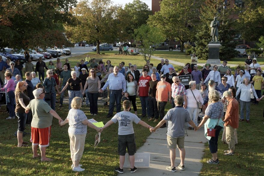 FILE - In this Sept. 12, 2017, file photo, a chorus of "We Shall Overcome" rises from a gathering against racism in Broad Street Park in Claremont, N.H. The demonstration was inspired by violence in the preceding month against an 8-year-old biracial boy who was nearly hanged while he played with a group of teenagers outside his home. On Tuesday, Dec. 10, 2019, New Hampshire released a set of guidelines to help law enforcement agencies better handle hate crimes in the wake of a series of racial incidents in the state. (James M. Patterson/The Valley News via AP, File)