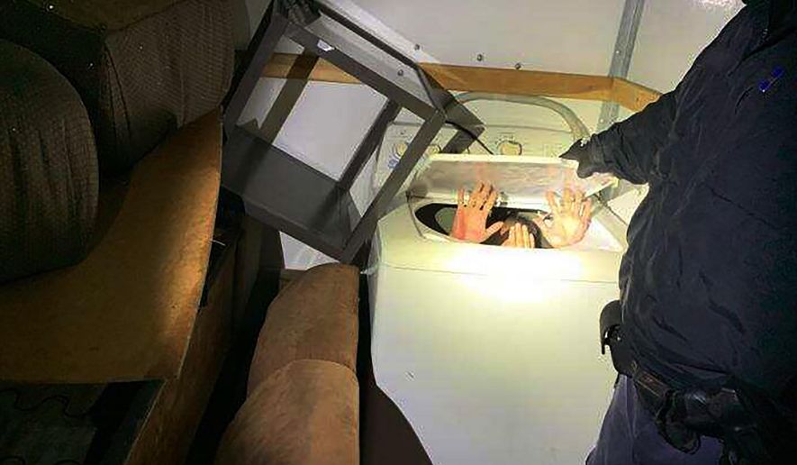 This photo released Monday, Dec. 9, 2019 by U.S. Customs and Border Protection (CBP) shows hands held up by a person or persons hiding in a washing machine, among 11 Chinese nationals found by CBP agents hiding in furniture and appliances inside a moving truck stopped Saturday, Dec. 7, while entering the U.S. from Mexico at the San Ysidro border crossing near San Diego, federal officials said. The truck driver, a 42-year-old U.S. citizen, was arrested on suspicion of human smuggling, according to a statement. (U.S. Customs and Border Protection via AP)