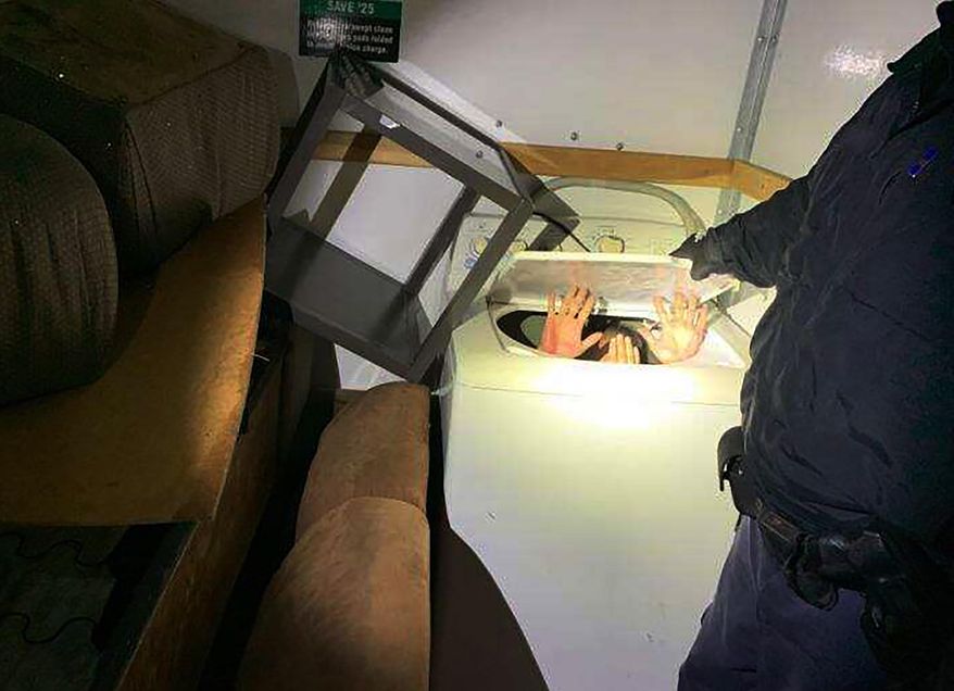 This photo released Monday, Dec. 9, 2019 by U.S. Customs and Border Protection (CBP) shows hands held up by a person or persons hiding in a washing machine, among 11 Chinese nationals found by CBP agents hiding in furniture and appliances inside a moving truck stopped Saturday, Dec. 7, while entering the U.S. from Mexico at the San Ysidro border crossing near San Diego, federal officials said. The truck driver, a 42-year-old U.S. citizen, was arrested on suspicion of human smuggling, according to a statement. (U.S. Customs and Border Protection via AP)
