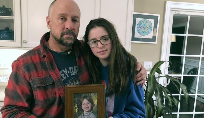 In this Dec. 3, 2019, photo, Mark Barden and his daughter Natalie Barden hold a photograph of Natalie&#x27;s late brother, Daniel, at their home in Newtown, Conn. Daniel died in the Dec. 14, 2012, Sandy Hook Elementary School shooting that killed 20 first-graders and six educators. Natalie, 17, is among Newtown students who have grown up to become young voices in the gun violence prevention movement. (AP Photo/Dave Collins)