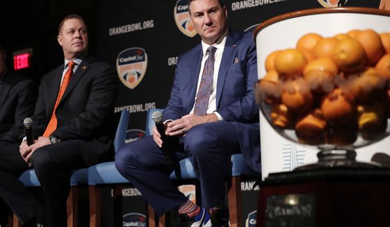 Virginia head coach Bronco Mendenhall, left, and Florida head coach Dan Mullen, right, listen during a news conference for the Orange Bowl NCAA college football game, Wednesday, Dec. 11, 2019, in Hollywood, Fla. Florida plays Virginia in the Orange Bowl Dec. 30 at Hard Rock Stadium in Miami Gardens, Fla. (AP Photo/Lynne Sladky)