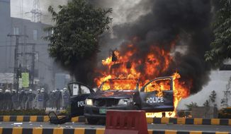 Police officers gather next to a burning police vehicles that were set on fire by angry lawyers during clashes in Lahore, Pakistan, Wednesday, Dec. 11, 2019. Hundreds of Pakistani lawyers, angered over alleged misbehavior of some doctors toward one of their colleagues last month, stormed a cardiology hospital in the eastern city of Lahore, setting off scuffles with the facility&#39;s staff and guards that left heart patients unattended for several hours. (AP Photo/K.M. Chaudary)