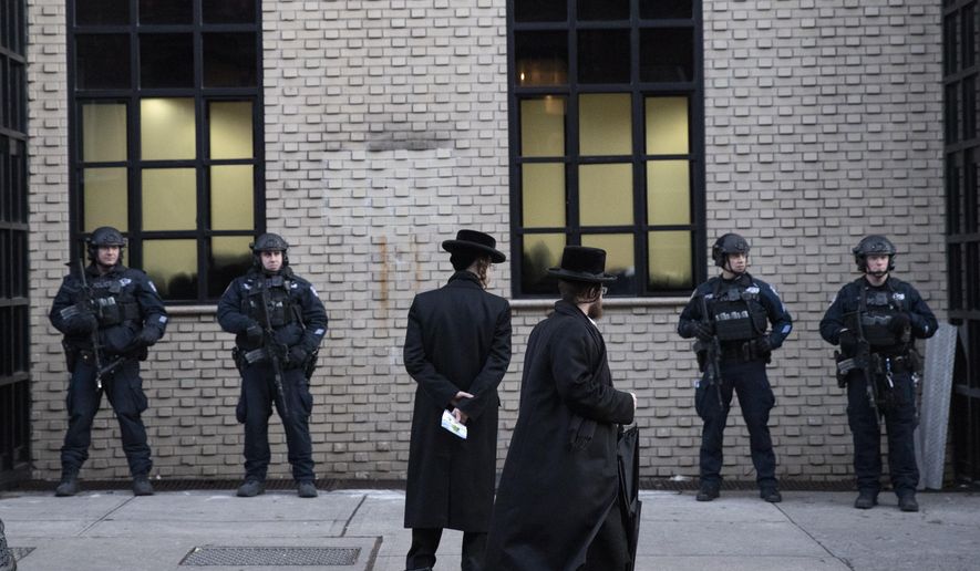 Orthodox Jewish men pass New York City police guarding a Brooklyn synagogue prior to a funeral for Mosche Deutsch, Wednesday, Dec. 11, 2019 in New York. Deutsch, a rabbinical student from Brooklyn, was killed Tuesday in the shooting inside a Jersey City, N.J. market. (AP Photo/Mark Lennihan)